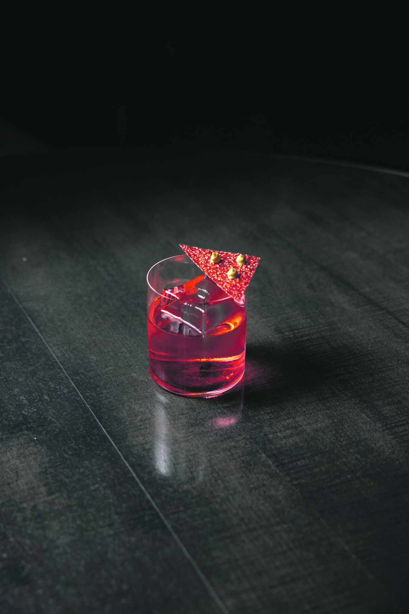 Dark background and wooden table with red cocktail on
