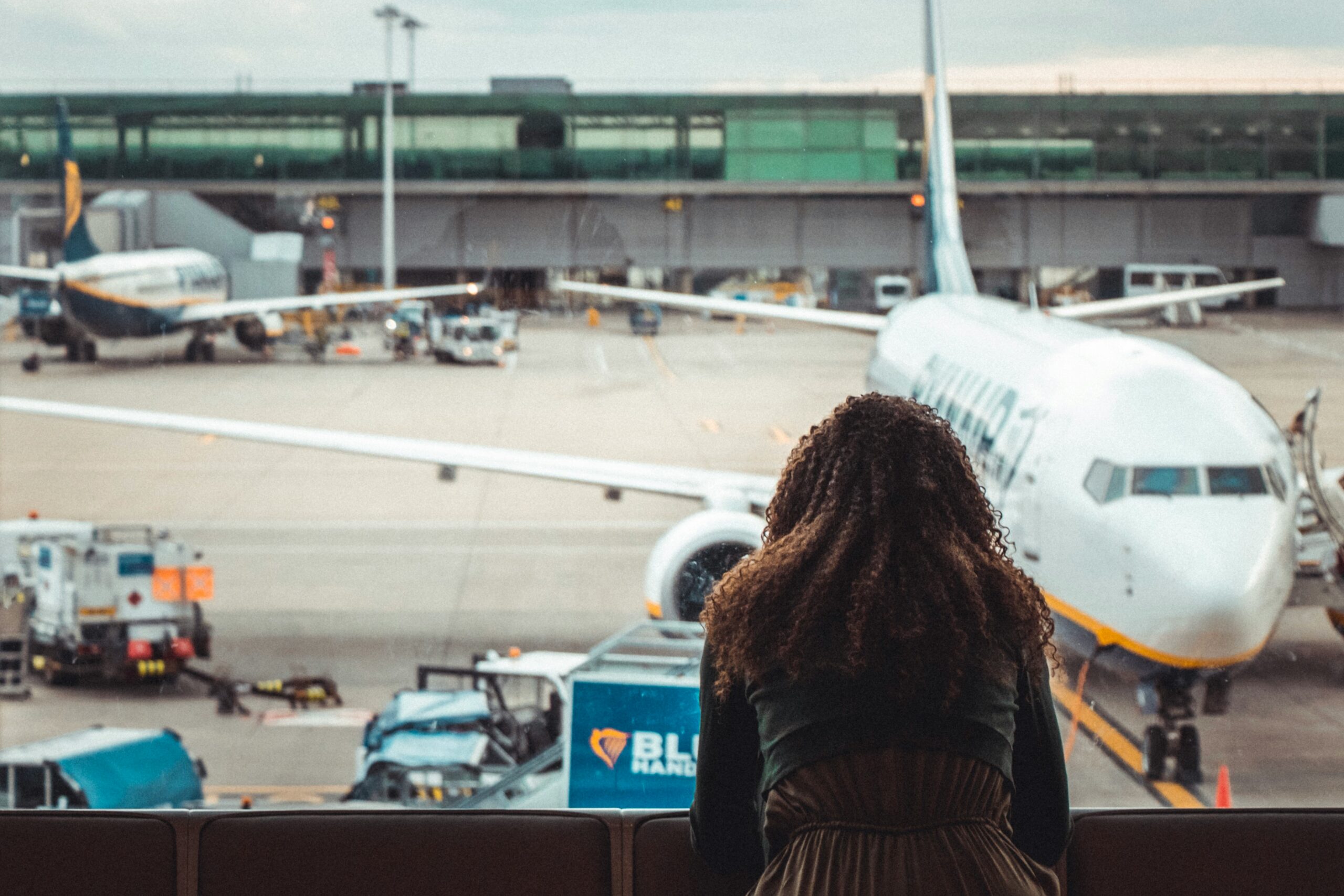 woman looking out of airport departure gate window at late plane