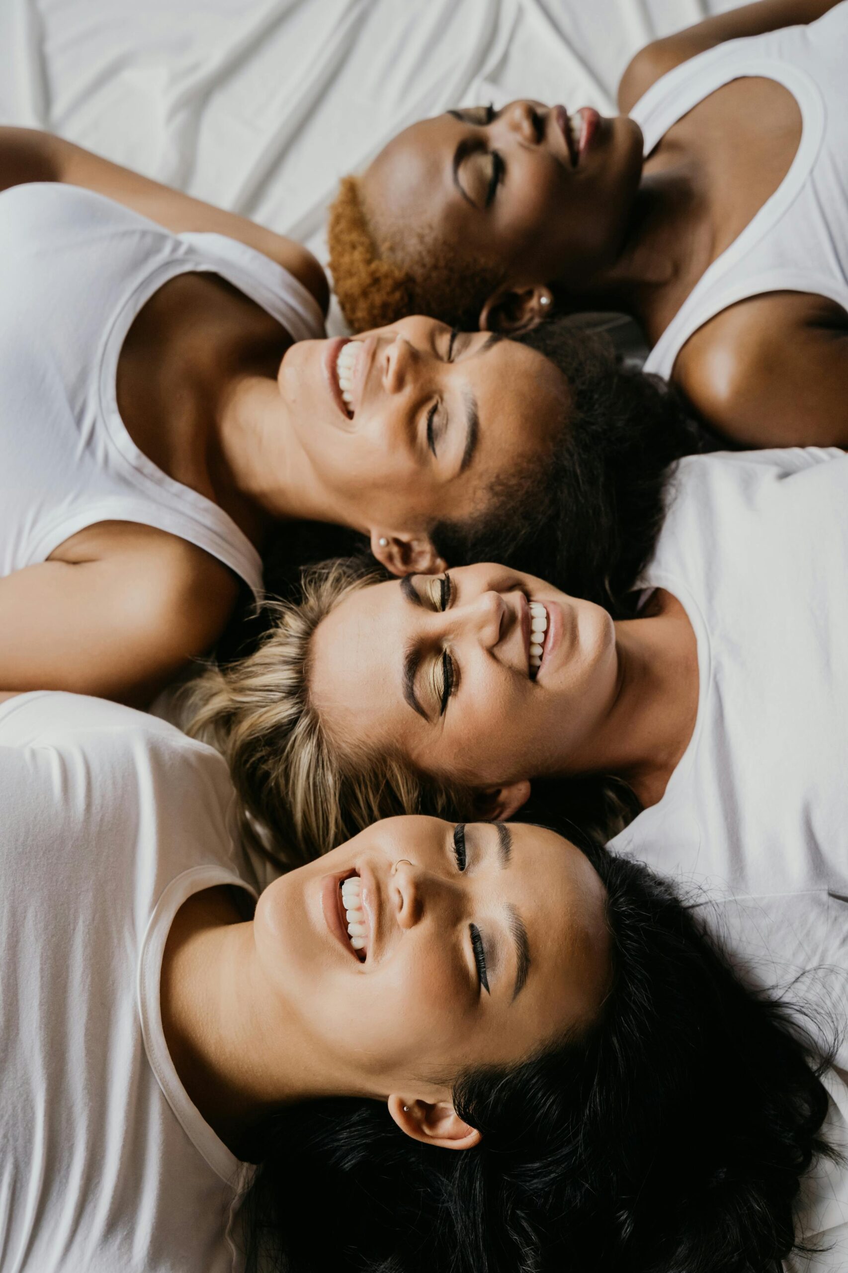 young female friends laughing smiling on bed