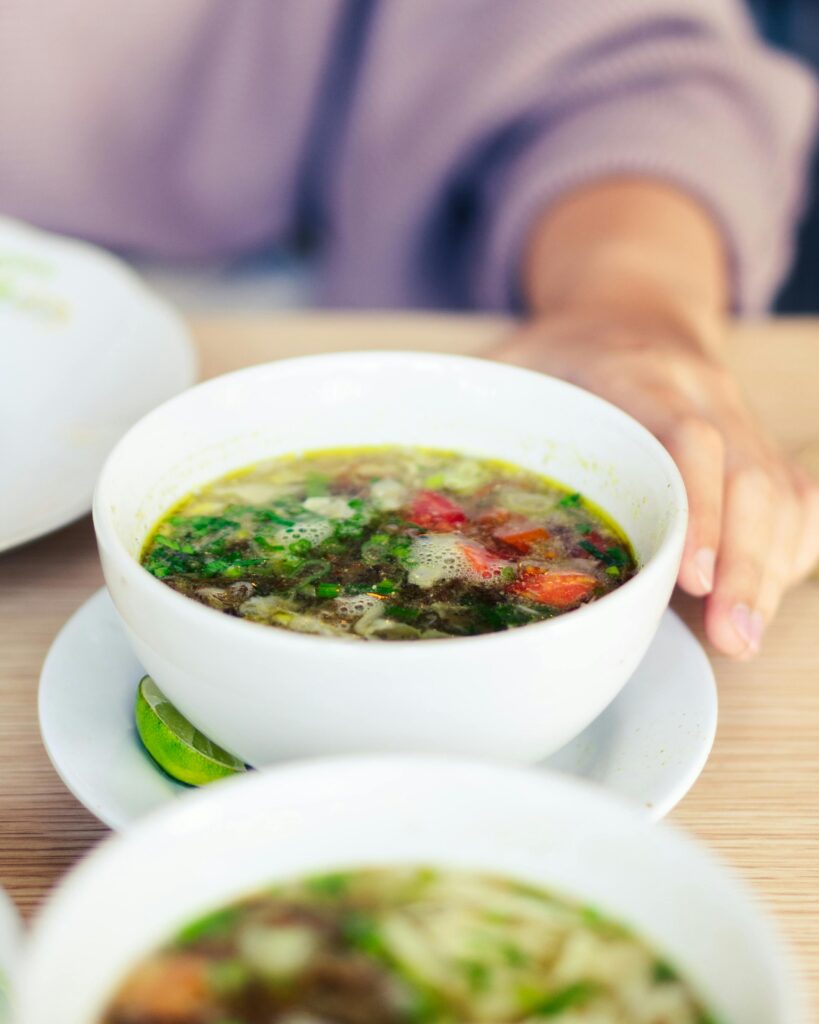 woman's hands on table touching a bowl of bone broth
