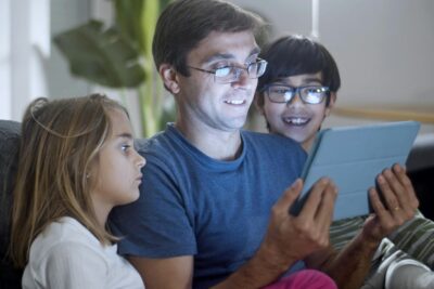 Parent looking at a tablet with a child either side
