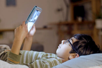 Children lying down looking at a tablet