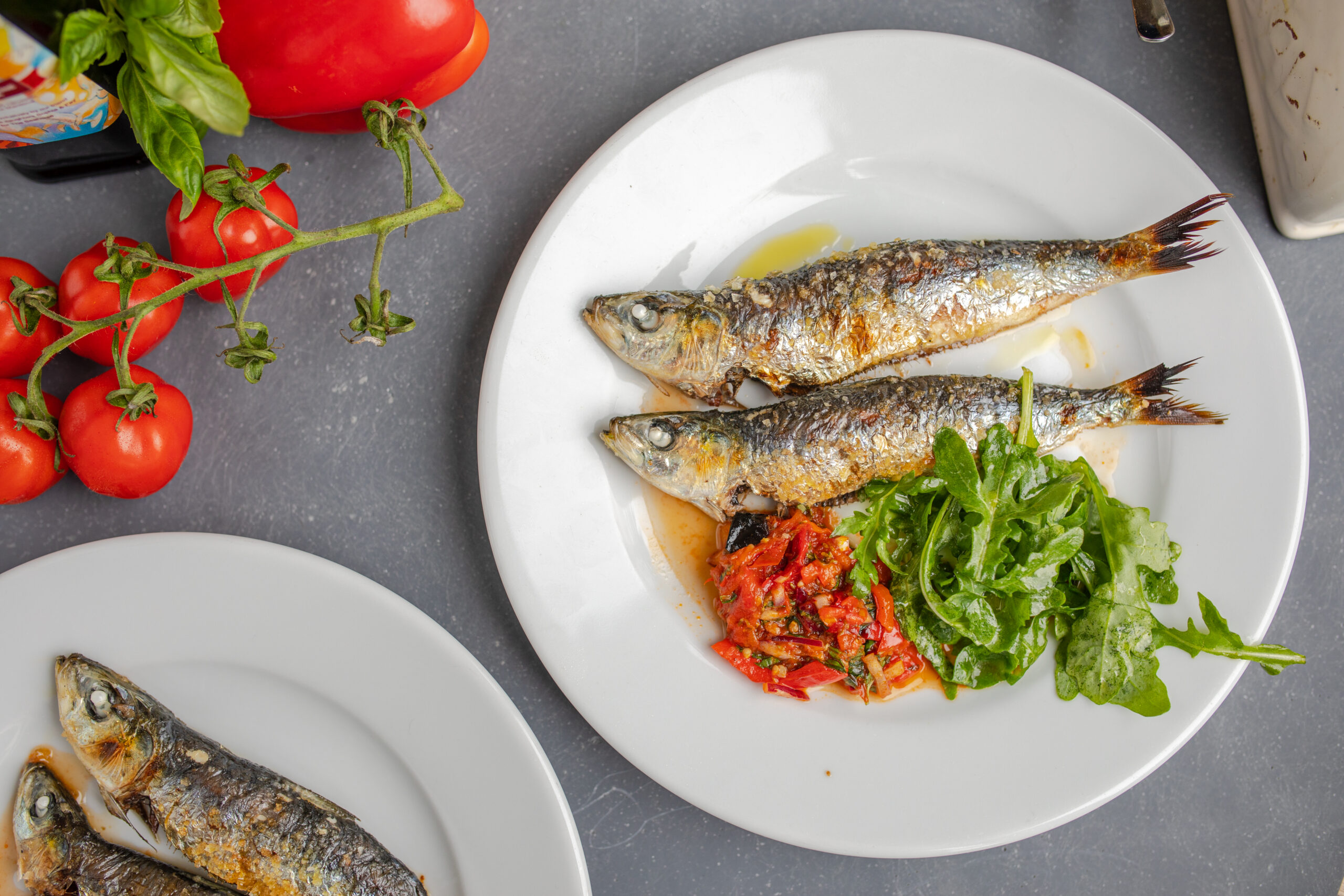 grilled sardines on a plate with salad and tomato salsa rossa