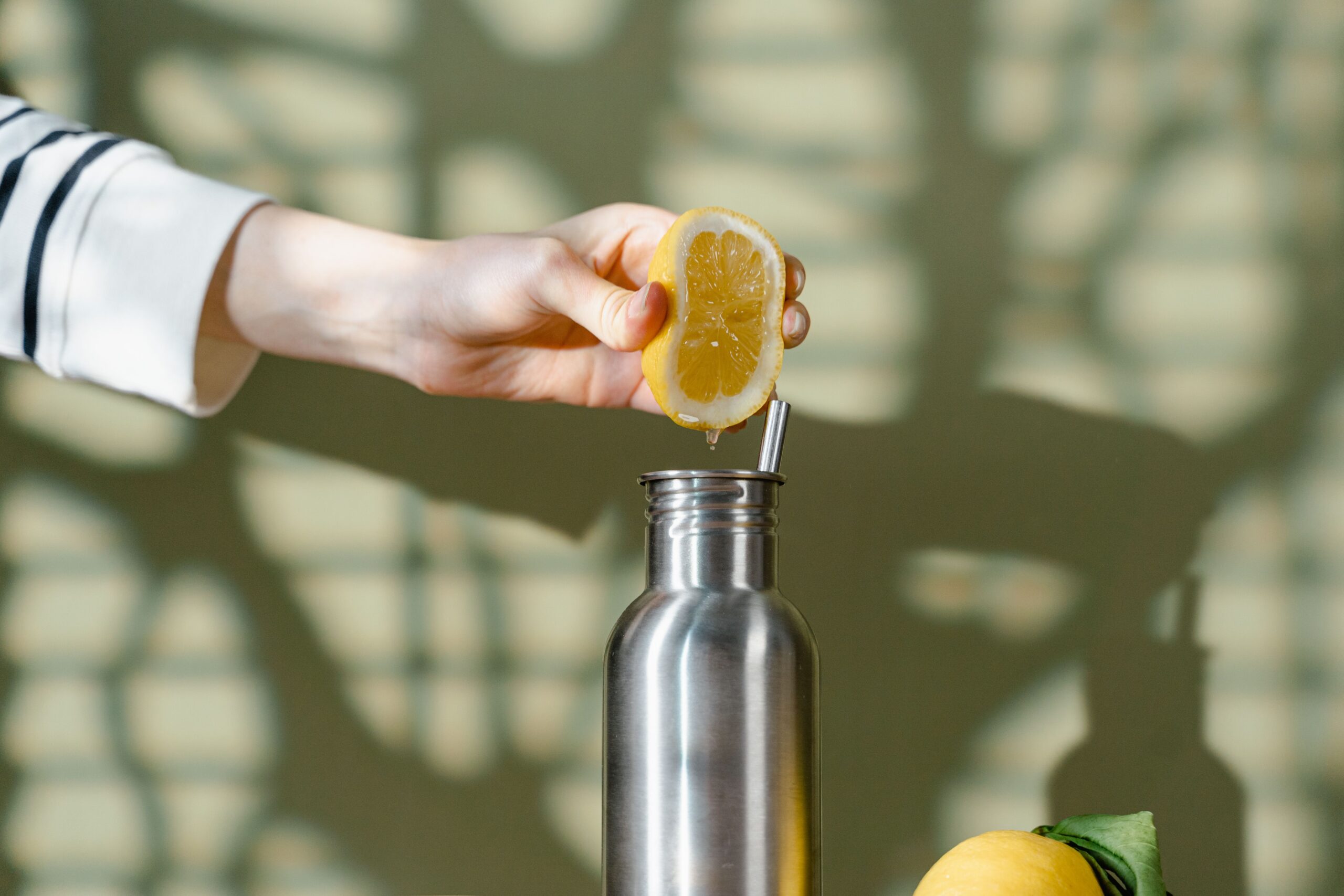 woman's arm squeezing lemon water into water bottle