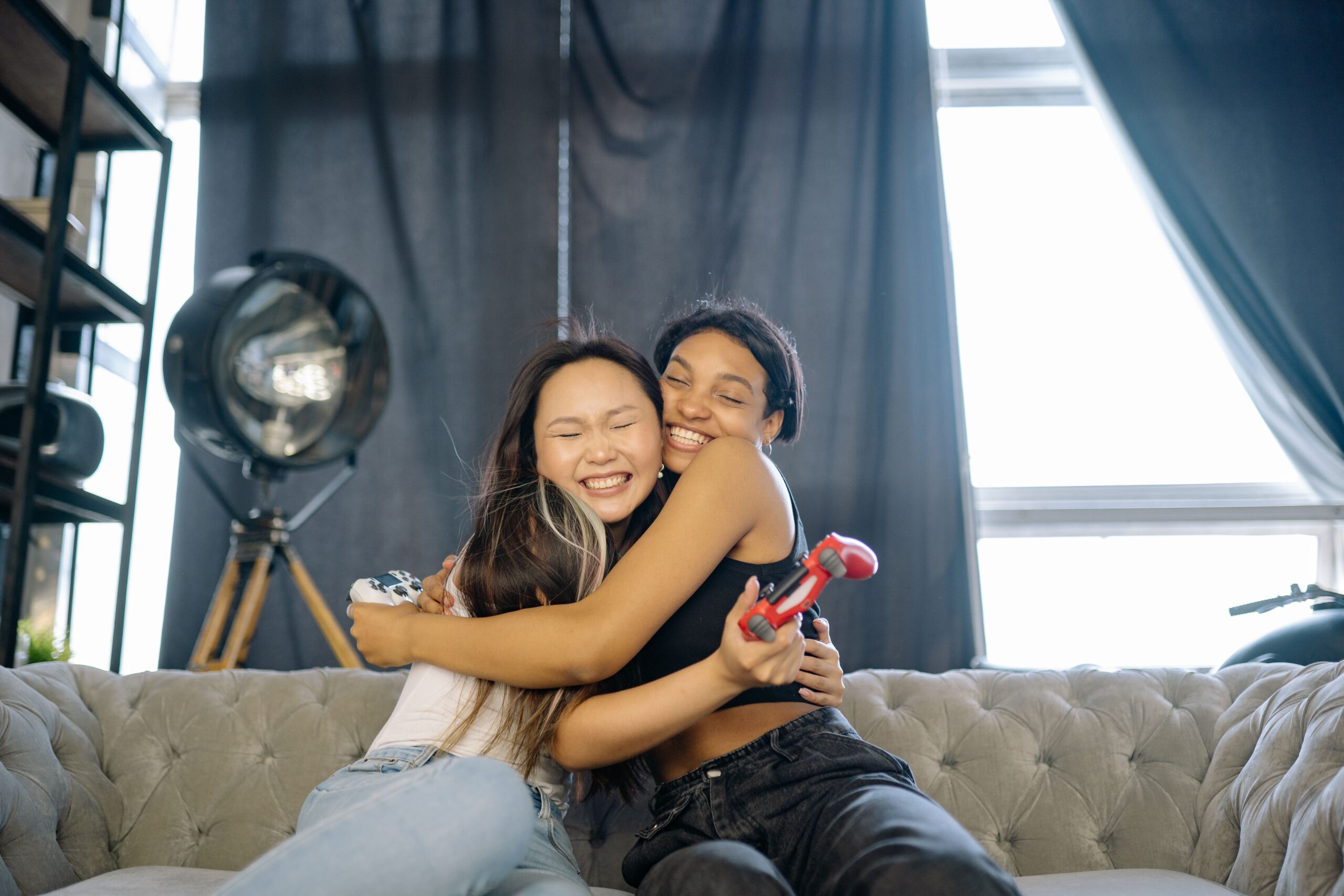 Teen girls hug while playing video games