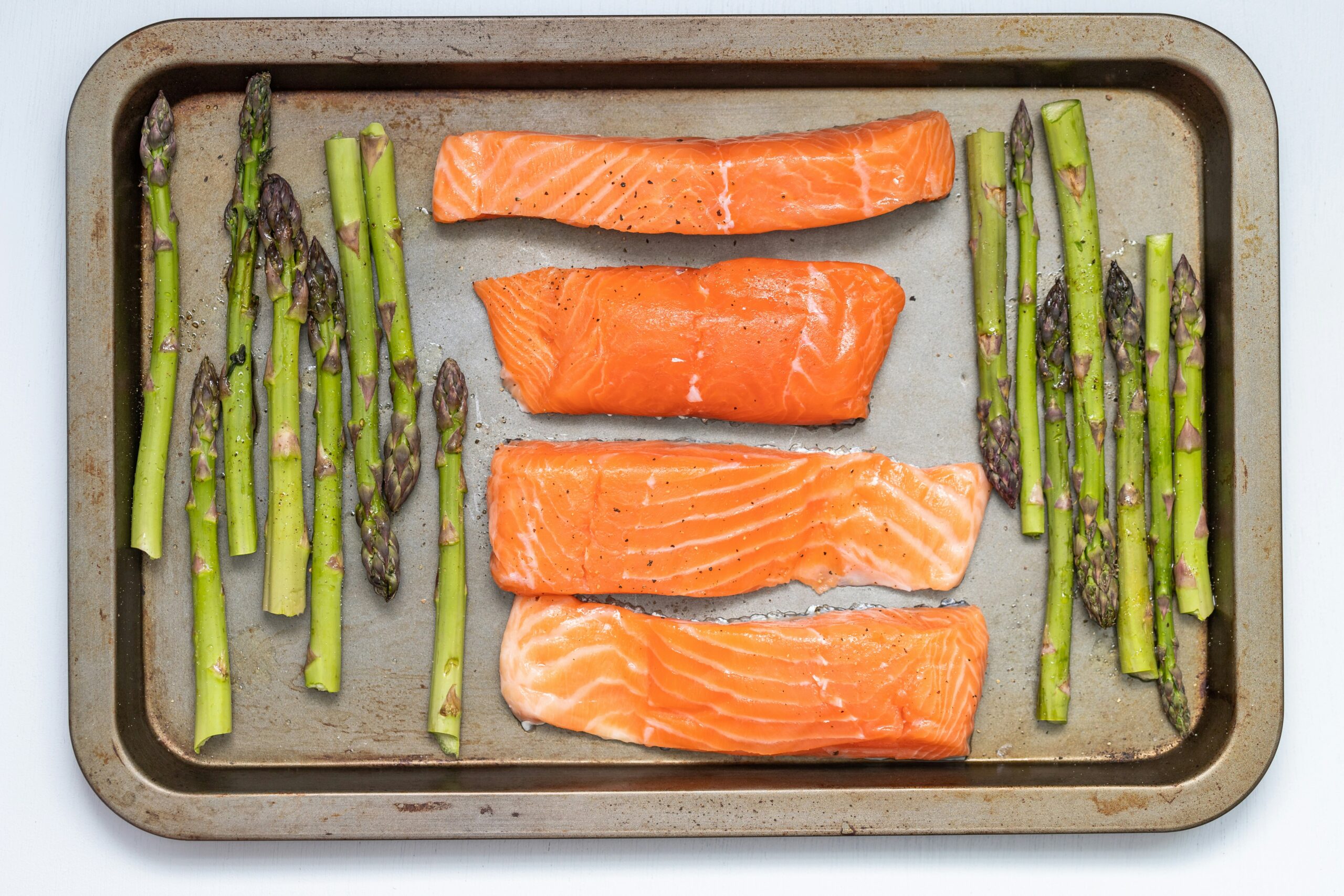 Salmon and asparagus on a tray with seasoning