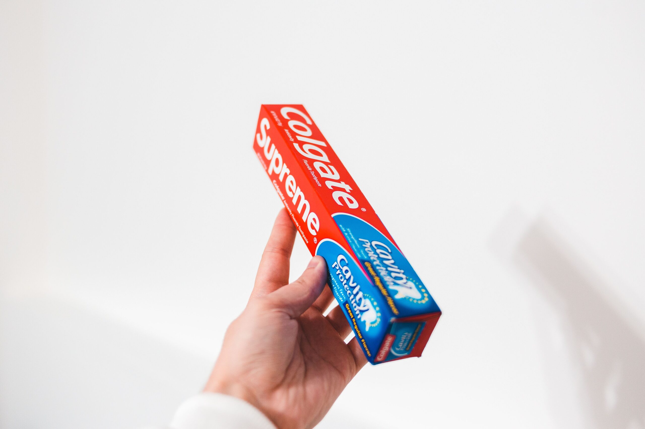 Hand holding toothpaste box with Colgate branding