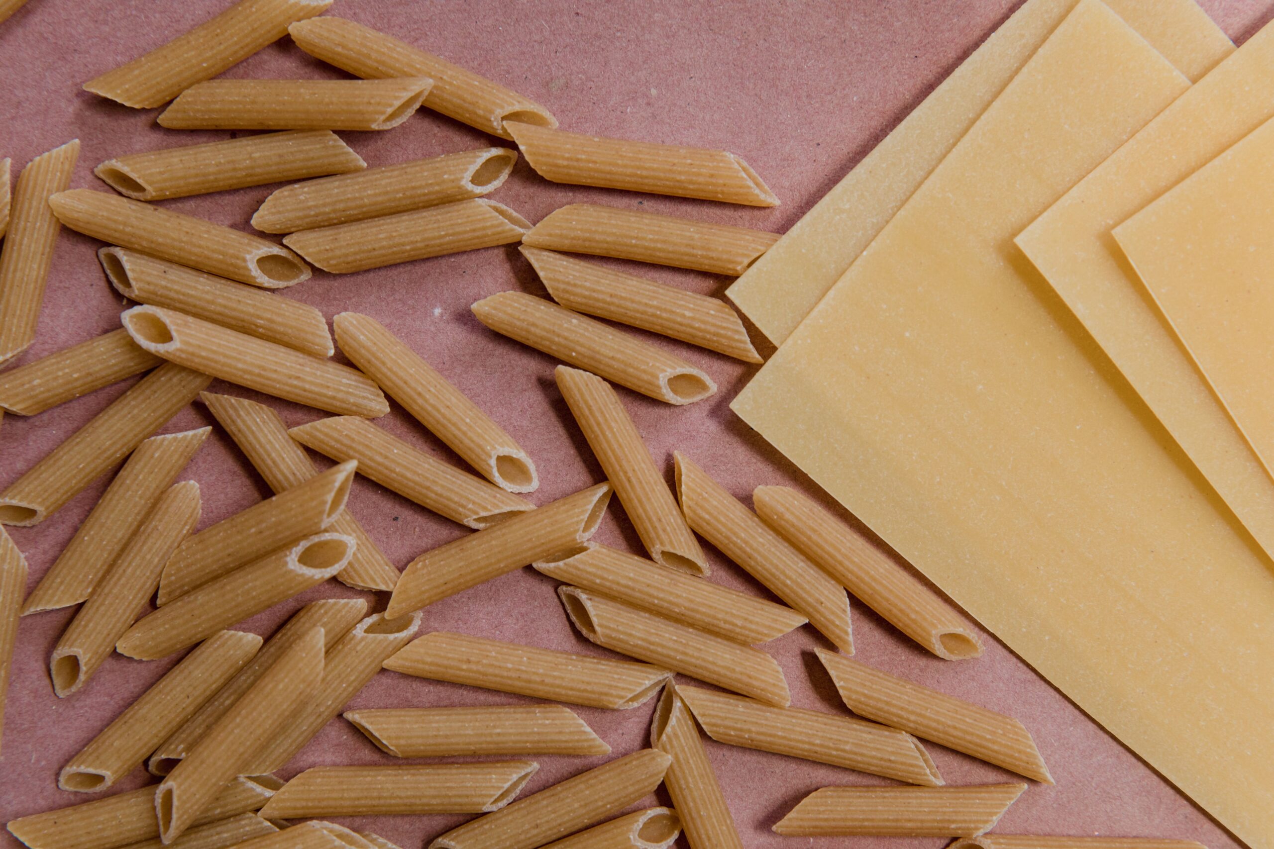 dusk pink surface with wholewheat penne and white lasagne sheets