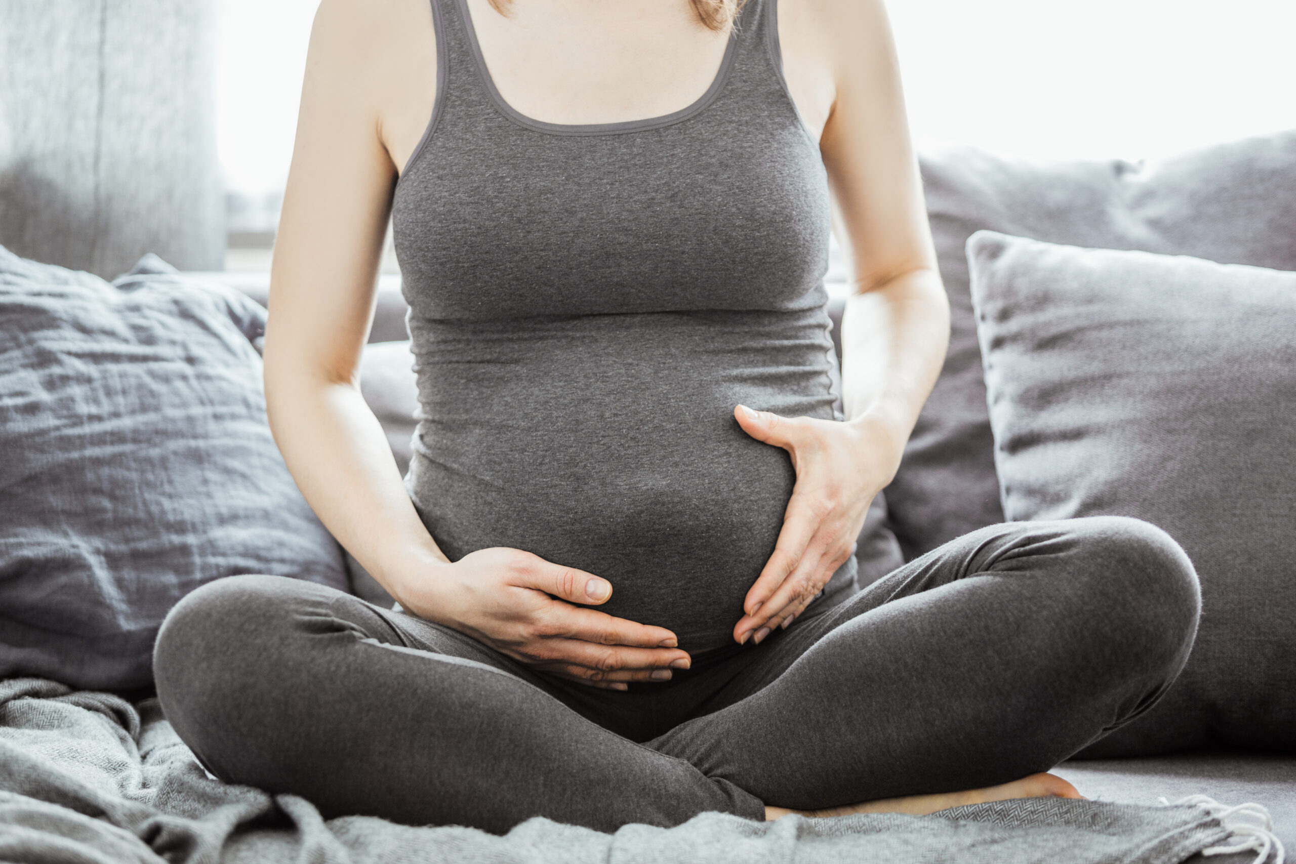 Pregnant woman sits on sofa
