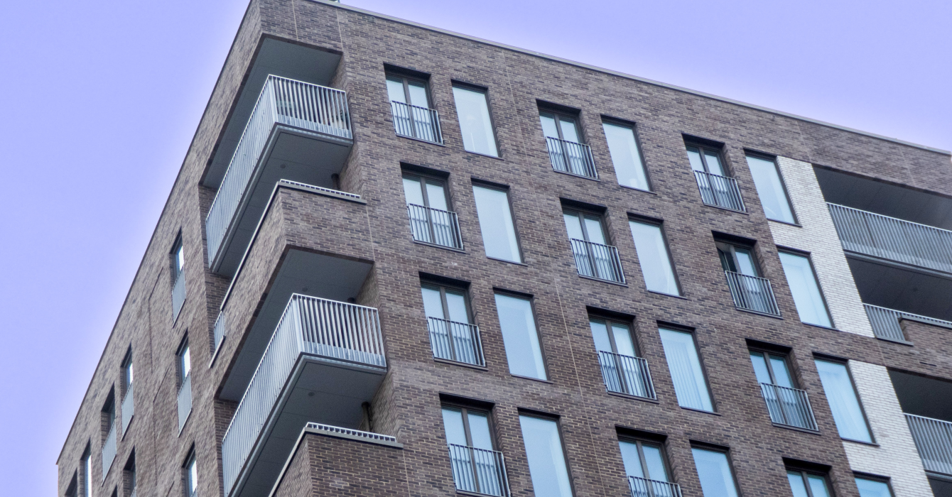 A shared ownership block of flats framed under a clear blue sky.