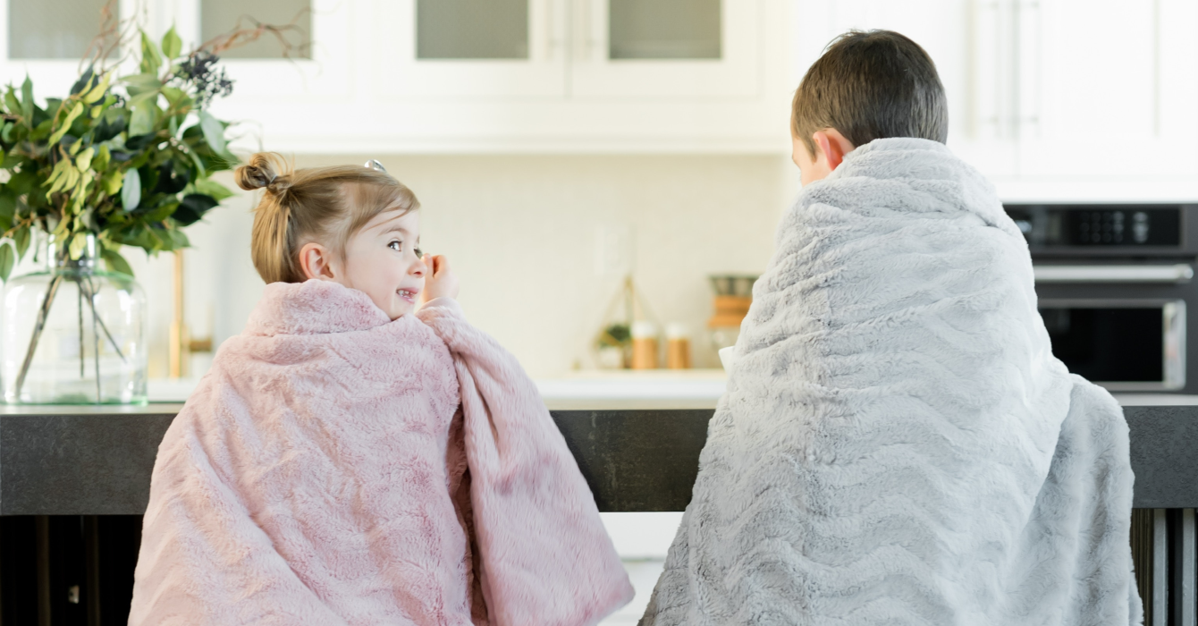 Snug under their faux fur throws, two kids hang out in their kitchen unaware a Kidde digital display carbon monoxide alarm is monitoring safety levels.