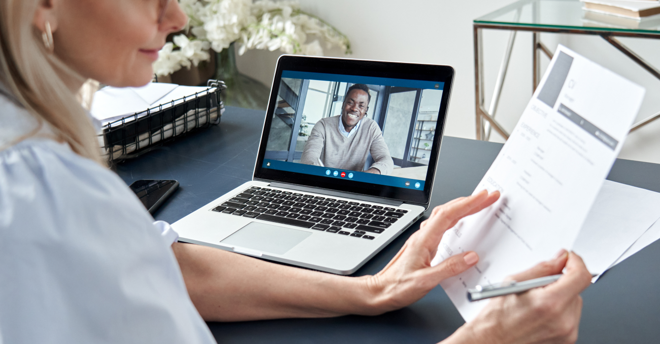 A woman interviews a potential candidate online using her MacBook.