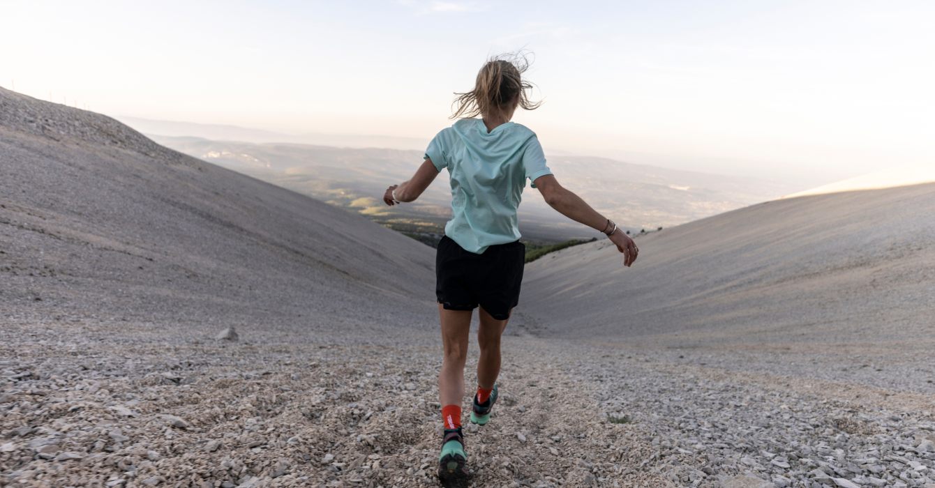 A young female jogger runs through a barren landscape.