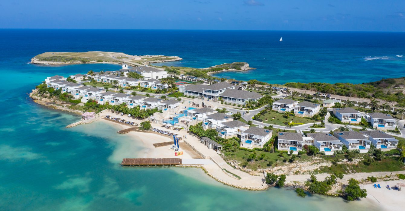 A beautiful aerial view of Hammock Cove Antigua highlights the sandy beaches and big blue sea.