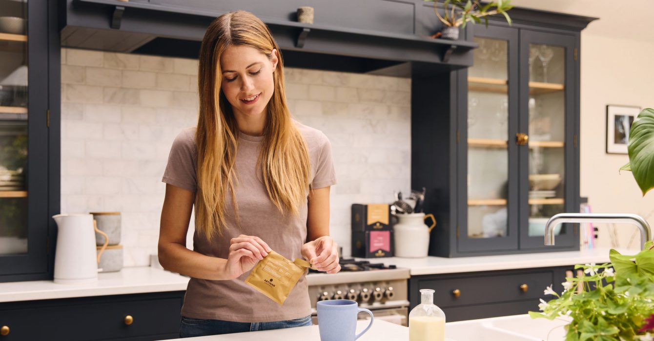 A young woman preparing a cup of Artisan Coffee in her kitchen.