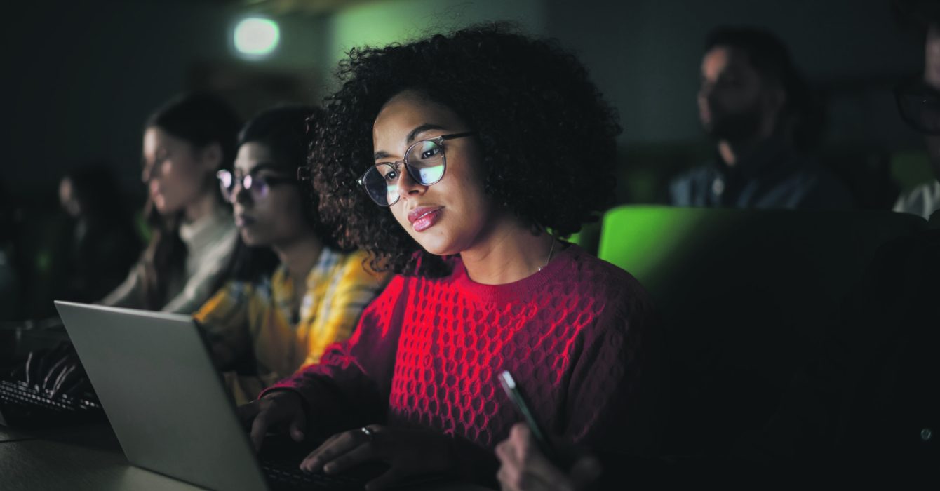 Beautiful Multiethnic African Female Student Studying in University with Diverse Classmates. Young Black Woman Using a Laptop Computer. Applying Her Knowledge to Acquire Academic Skills in Class