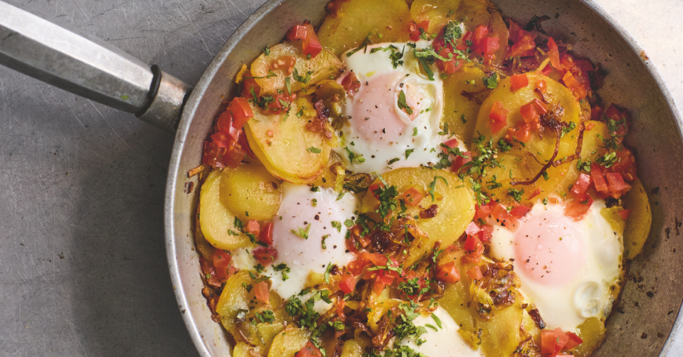 Cooked eggs and potato dish in a steel frying pan