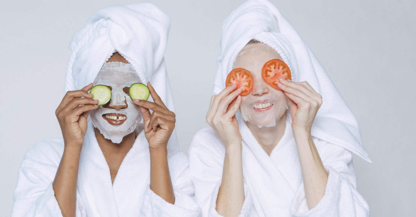 Two women wearing bath robes wearing sheet masks