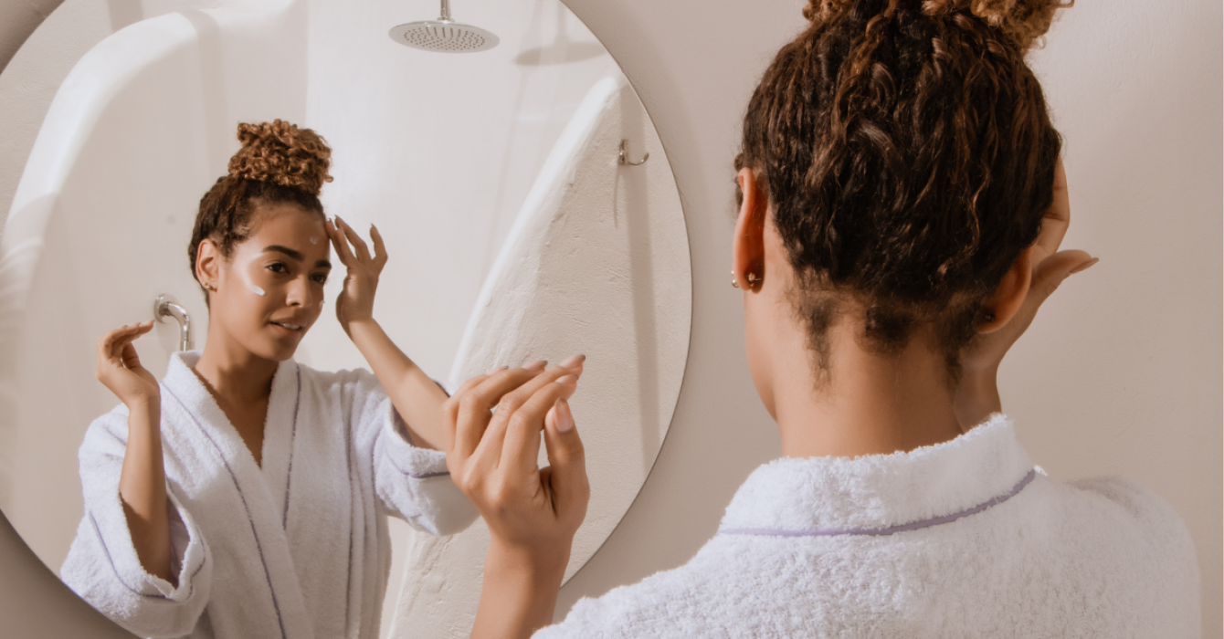 Woman applying skincare in mirror