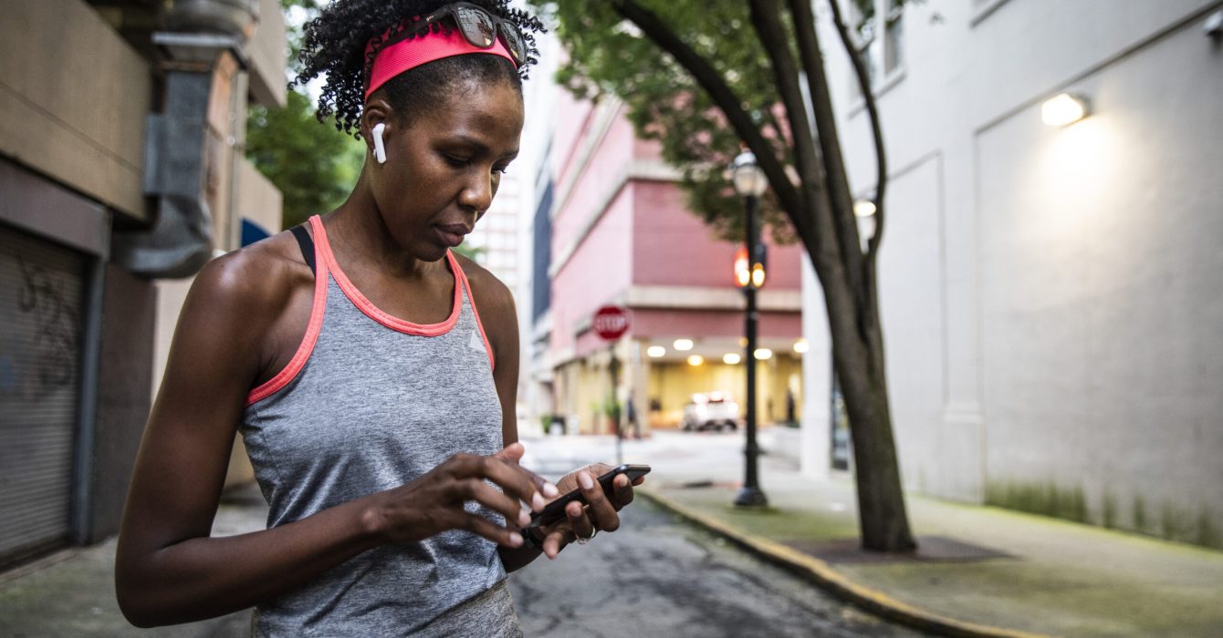 A woman checks her phone while out for a run.