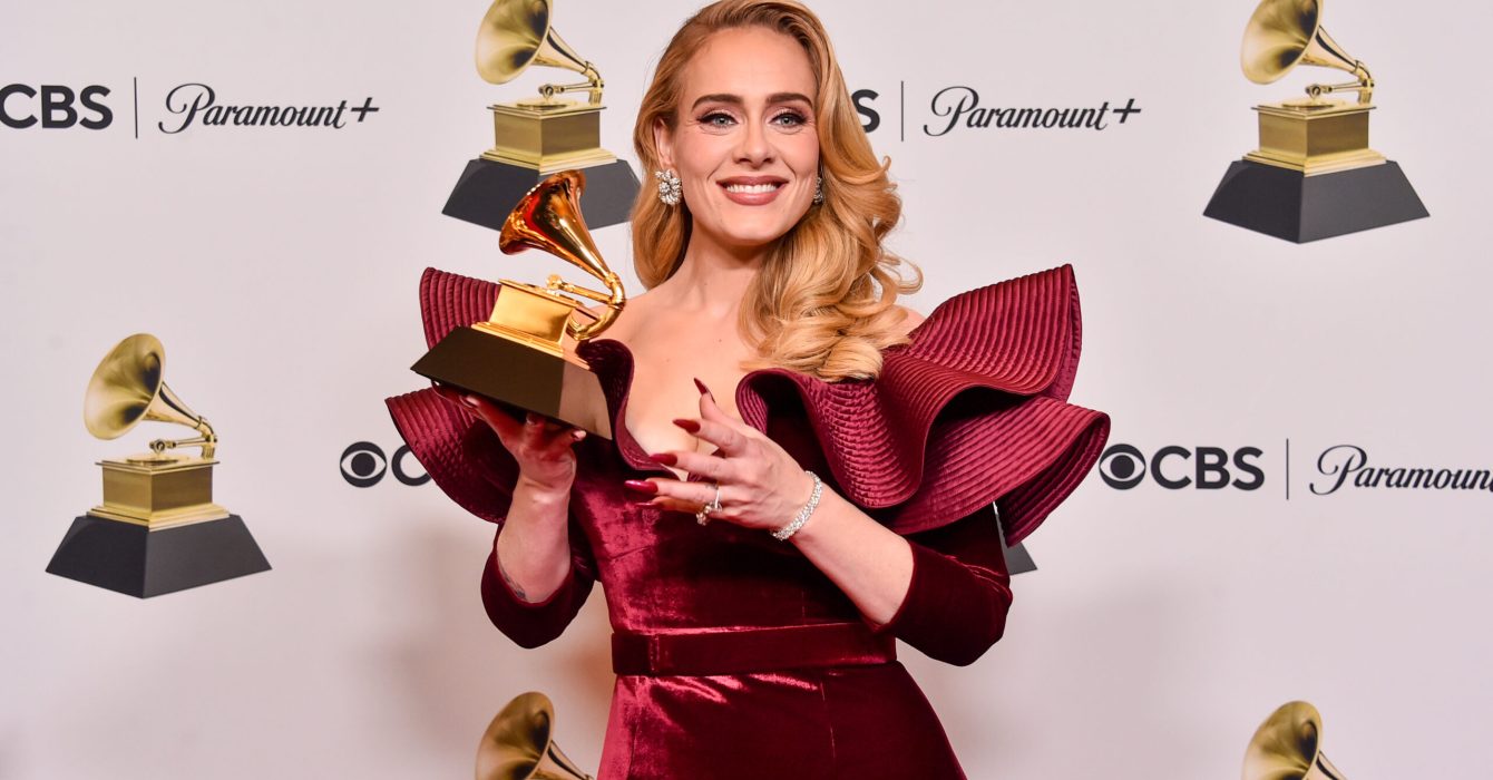 Dressed in a stylish red designer dress, singer Adele poses for the cameras with her award at the 65th GRAMMY Awards.