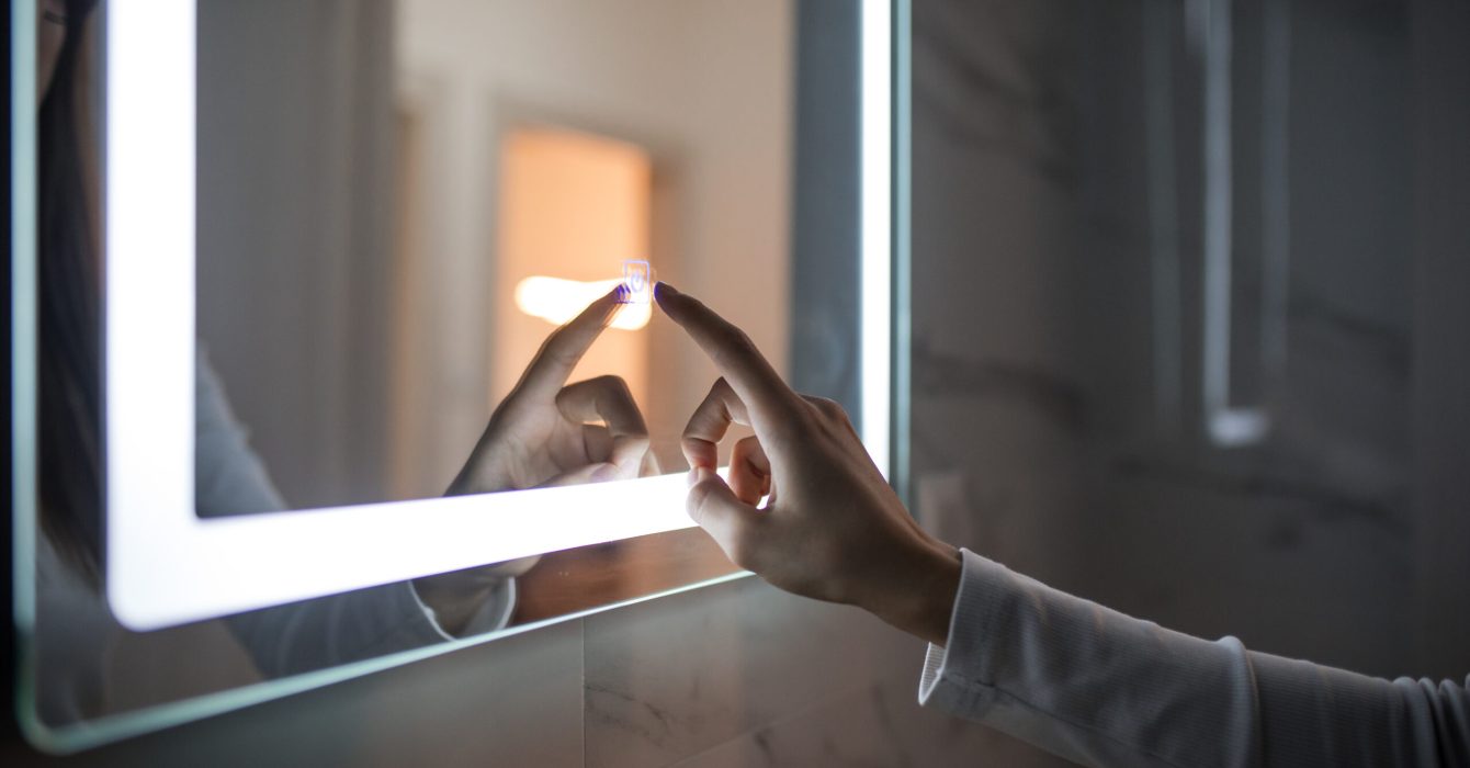 Unrecognisable woman turning on LED mirror at bathroom, image taken in Europe, Serbia, city of Niš