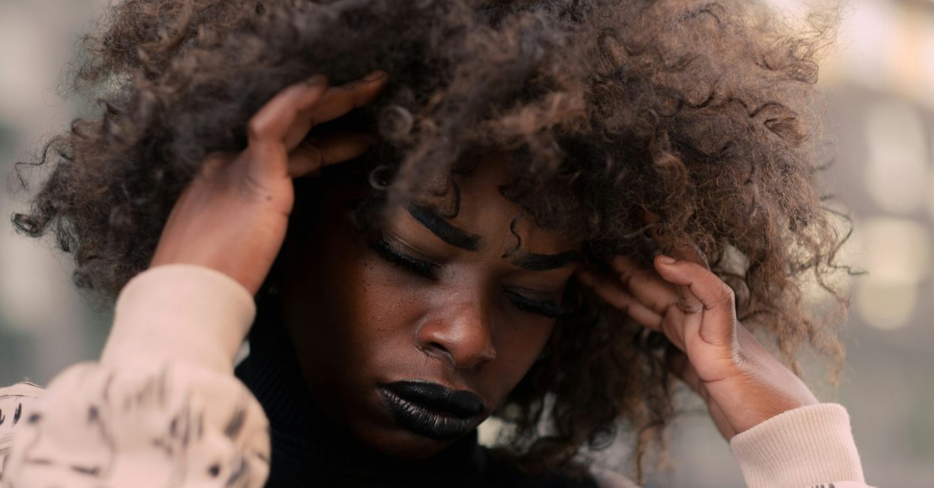 A black woman looking stressed with her head in her hands