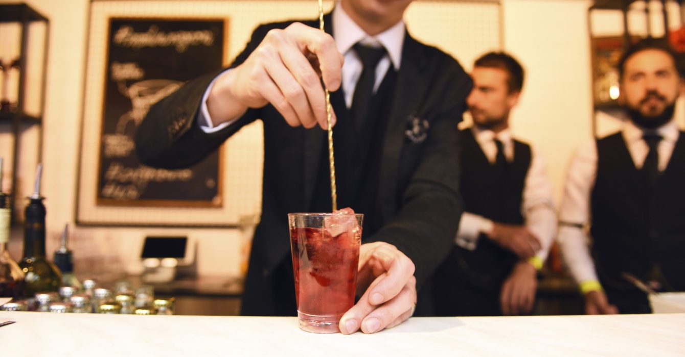 A mixologist serves a cocktail.