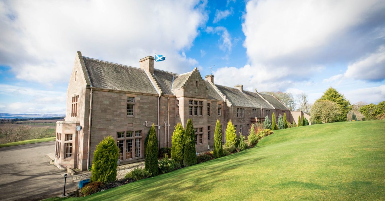 A scenic view of MurraysHall Hotel in the Scotland hills.