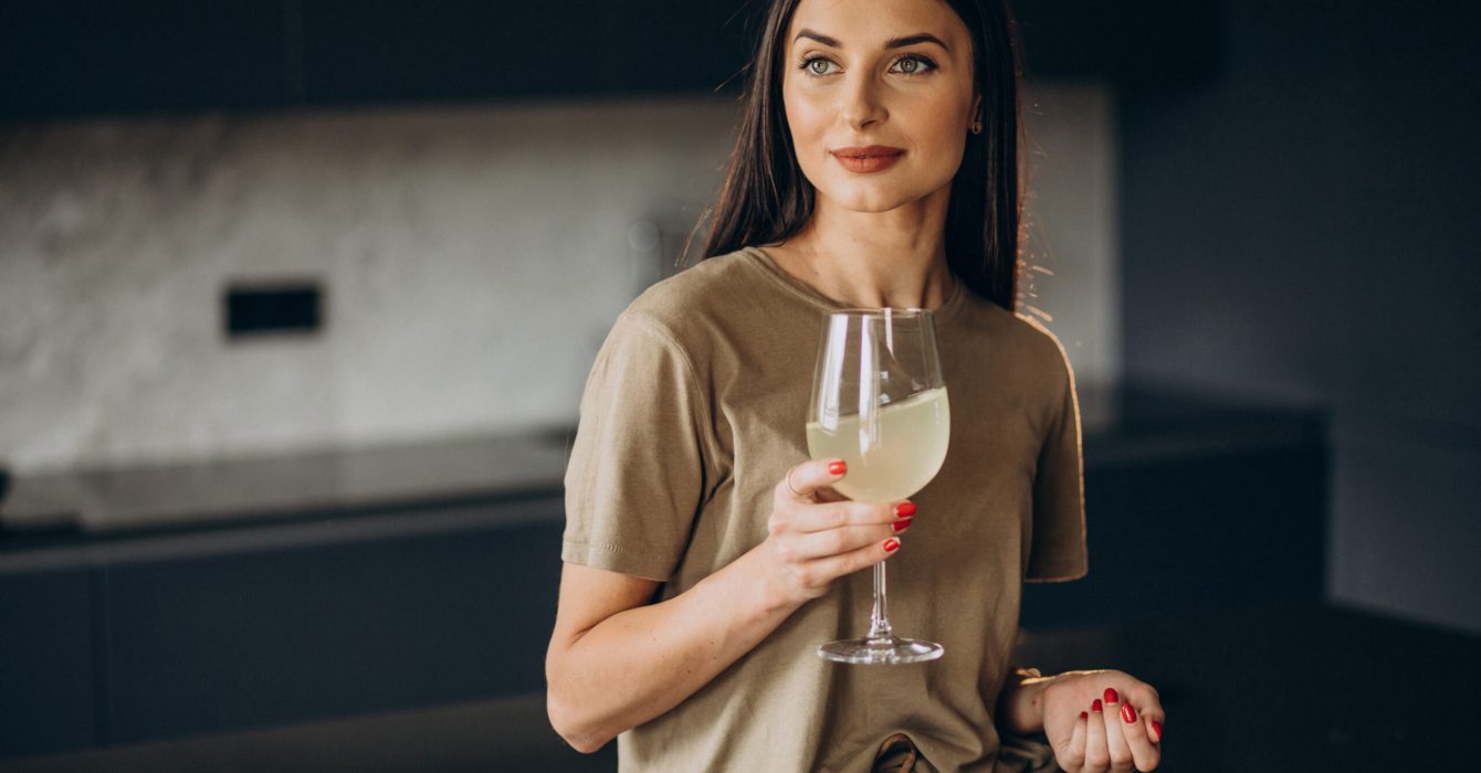 Young woman drinking lemonade from glass at the kitchen