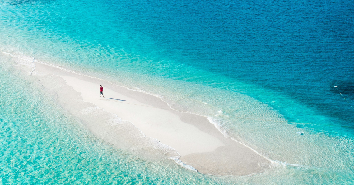 Travel lover walking on white sand strip in the Maldives