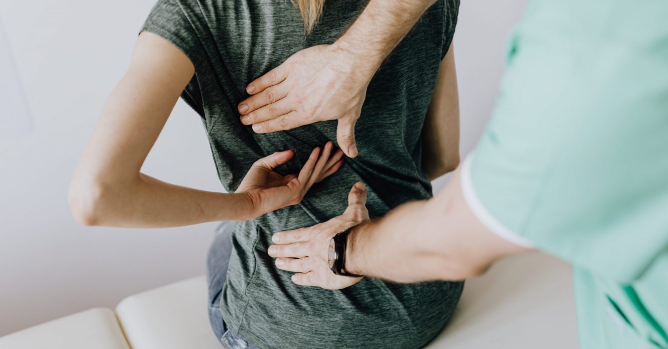 A doctor examining his patient for back pain.