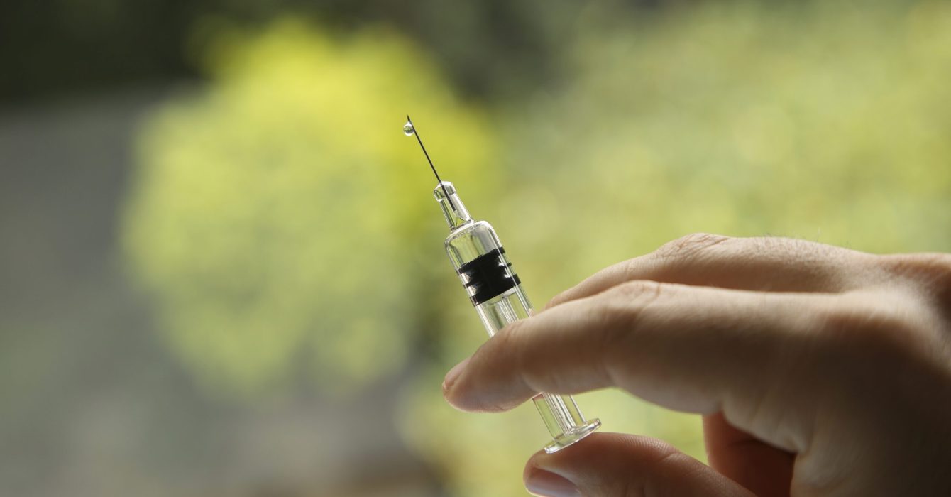 A closeup shot of a female holding a syringe, on a blurred background