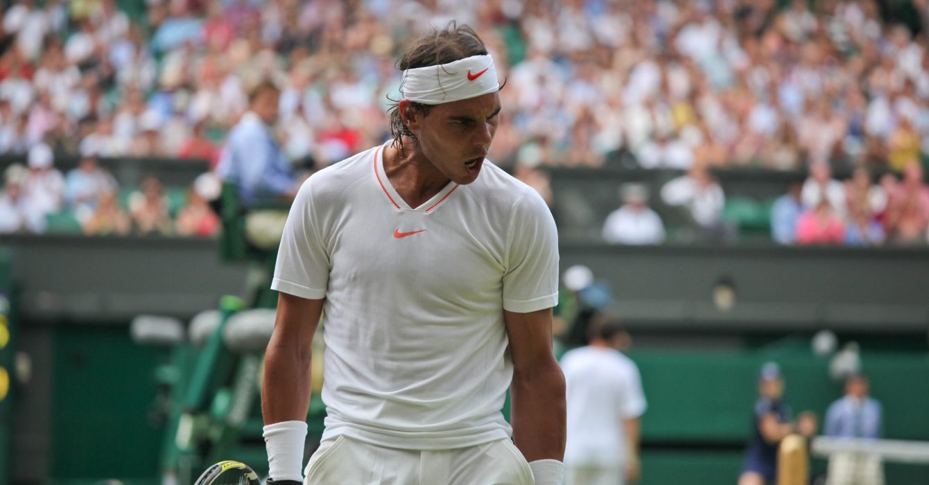 A tennis player takes their stance to serve at Wimbledon.