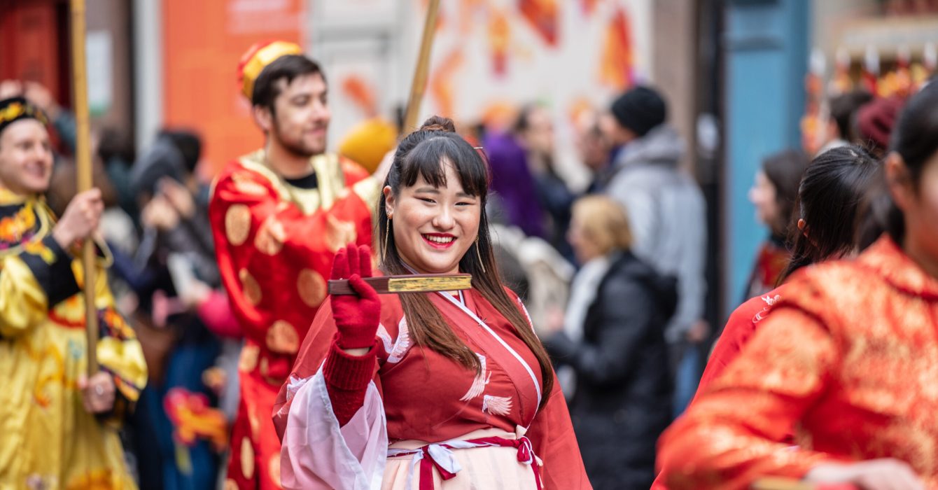 A woman in the Chinese New Year parade smiles and waves in Chinatown, London.