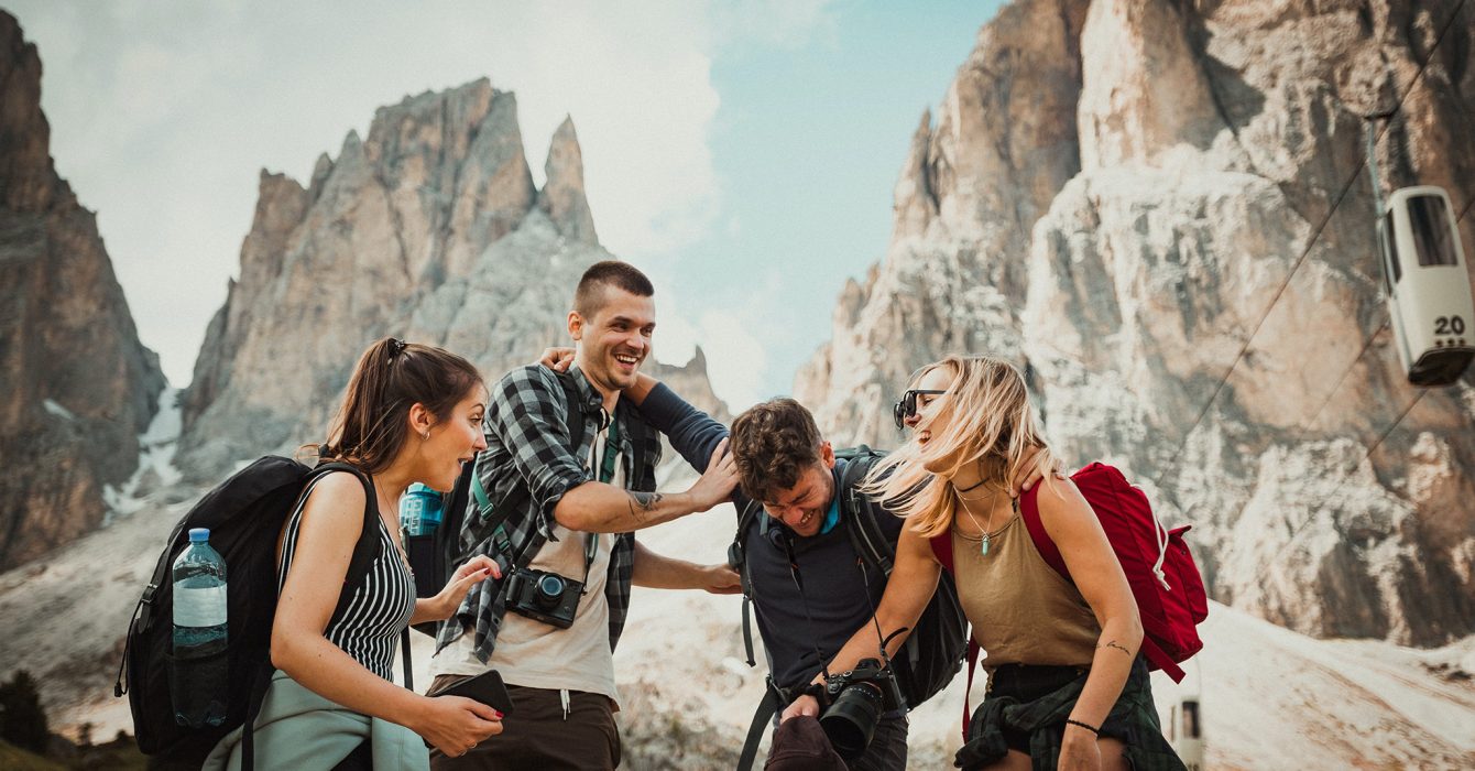 Two girls and two boys laughing, with a mountainous landscape in the background