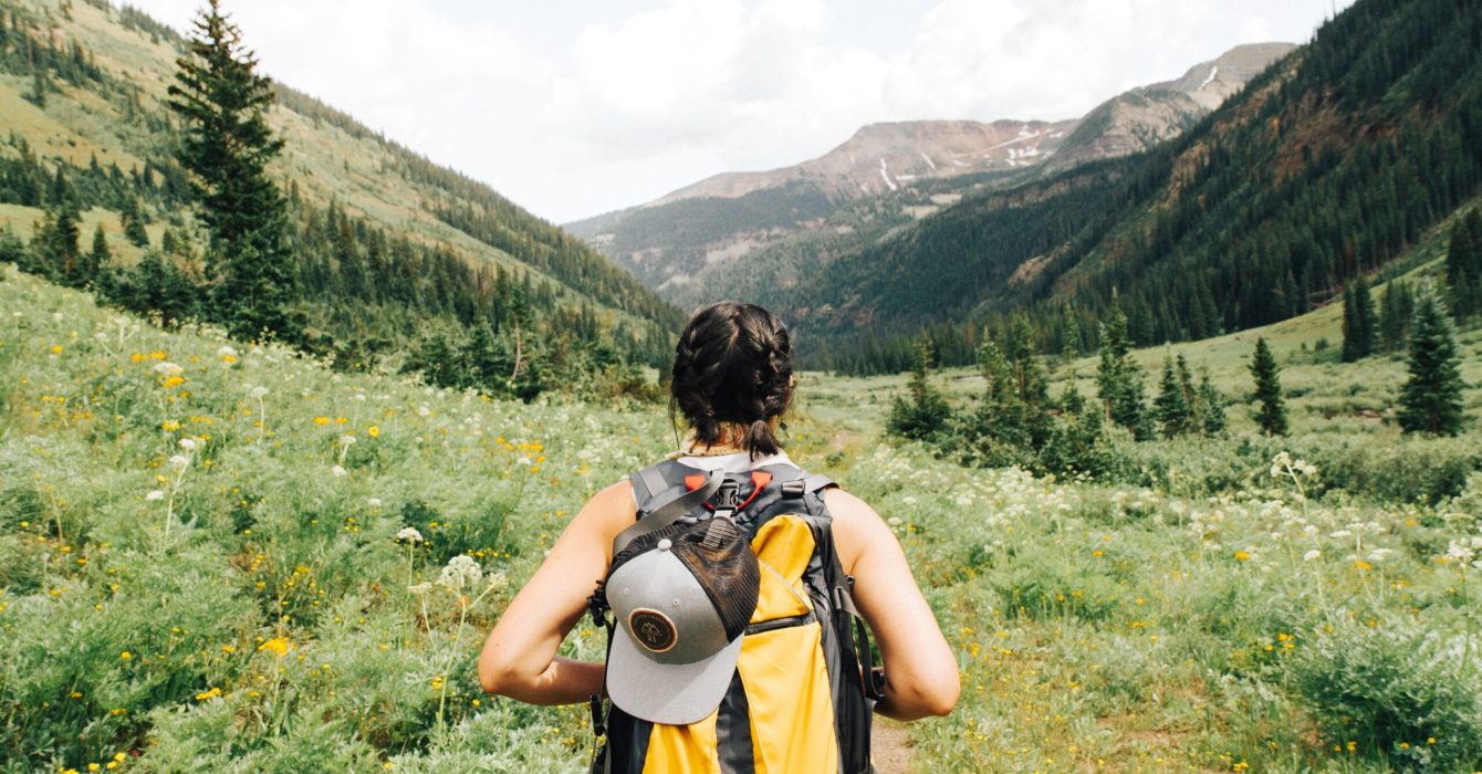 A solo female backpacker hikes through the mountains.