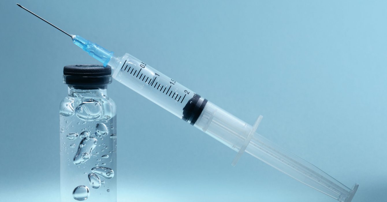 A syringe perched on top of a vial filled with salmon sperm serum.