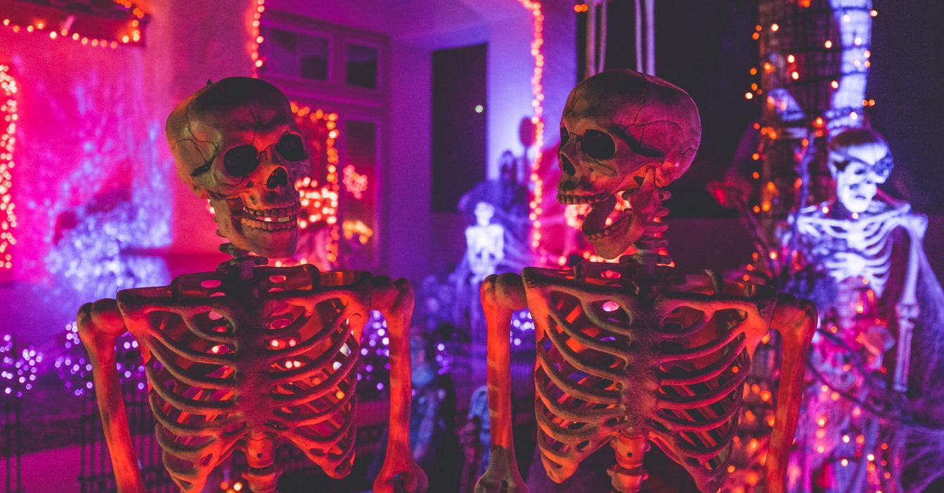 Two human skeletons stand guard at a Halloween party