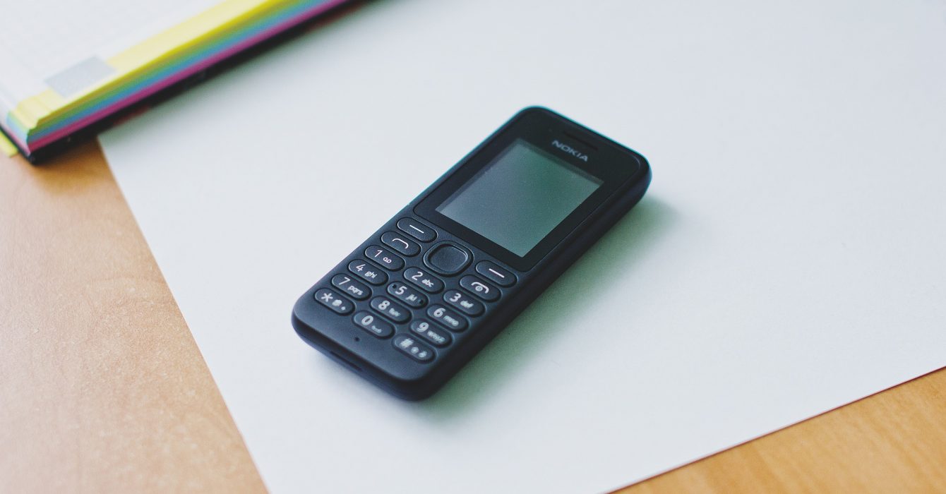 nokia feature phone on a sheet of white paper on a wooden table