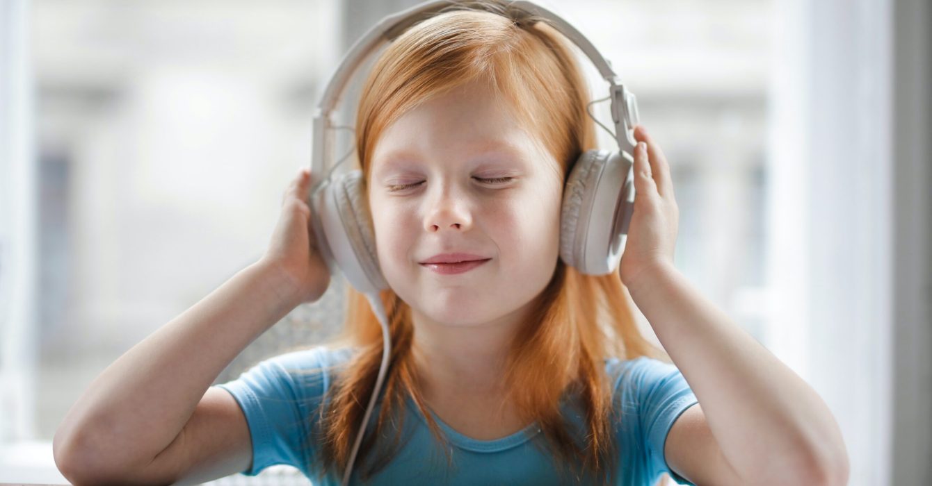 A young girl listens to music on her headphones.