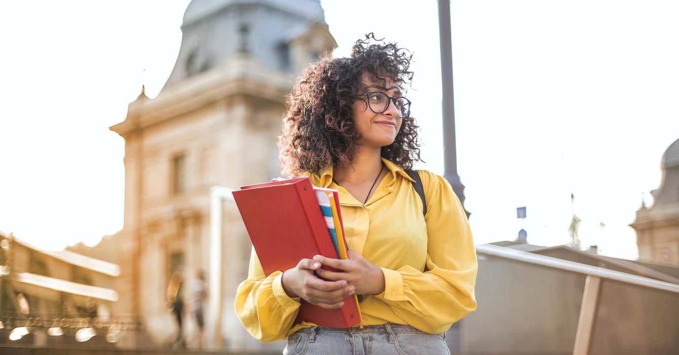 Woman in yellow jacket holding books