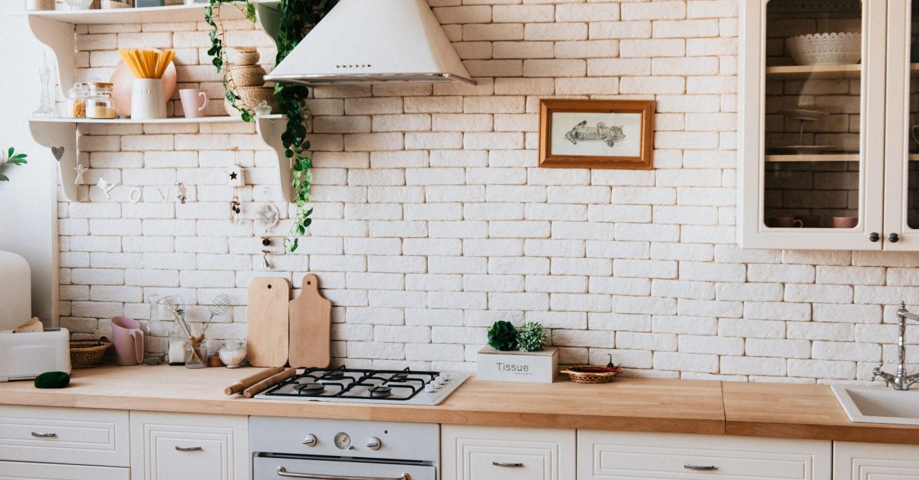 A white and beige kitchen with wood worktops.