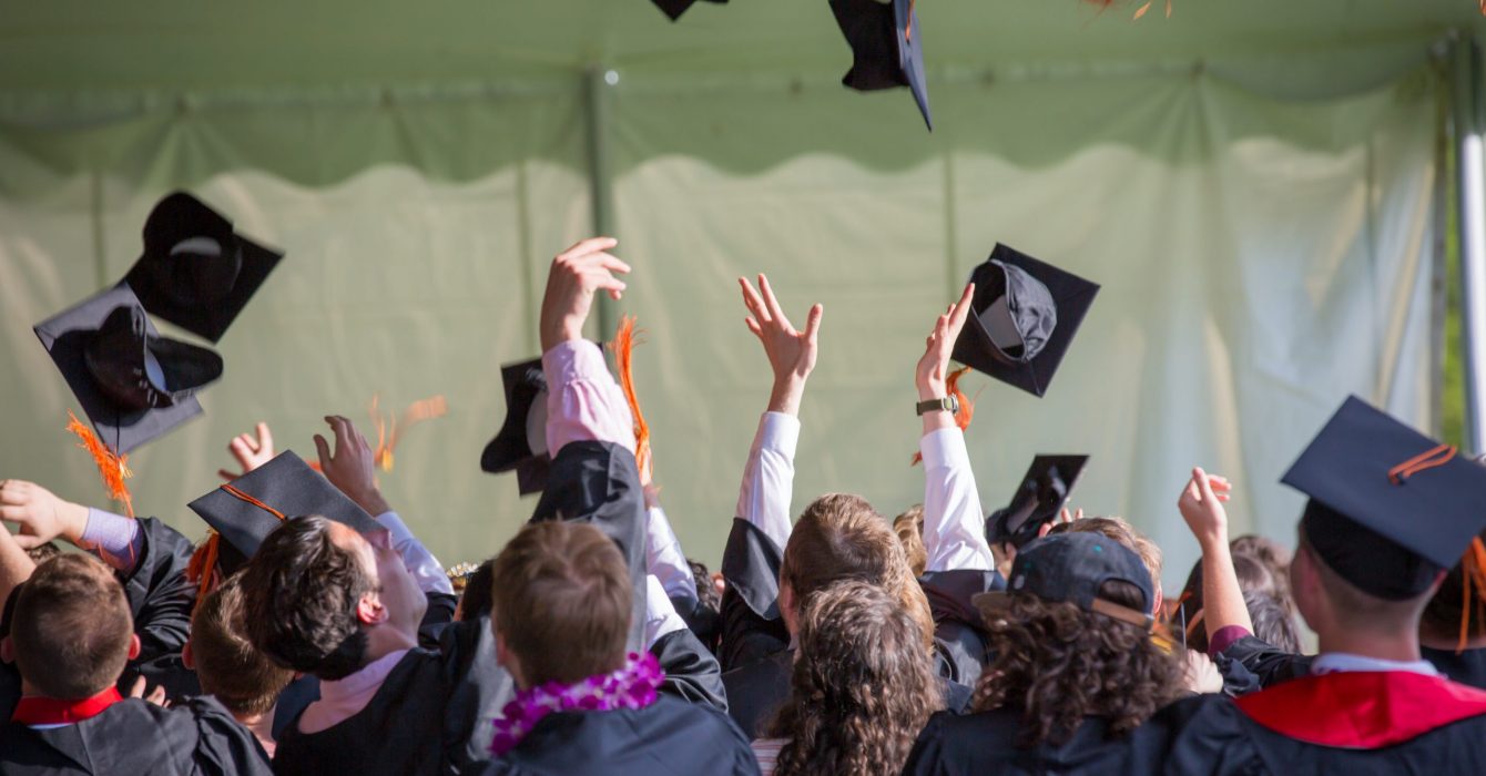 A group of graduates throwing their caps up in the air.