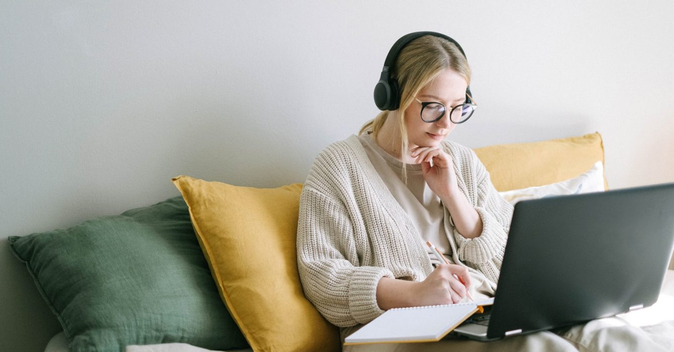 A woman takes notes listening to a podcast on ‘how to manage imposter syndrome?’.