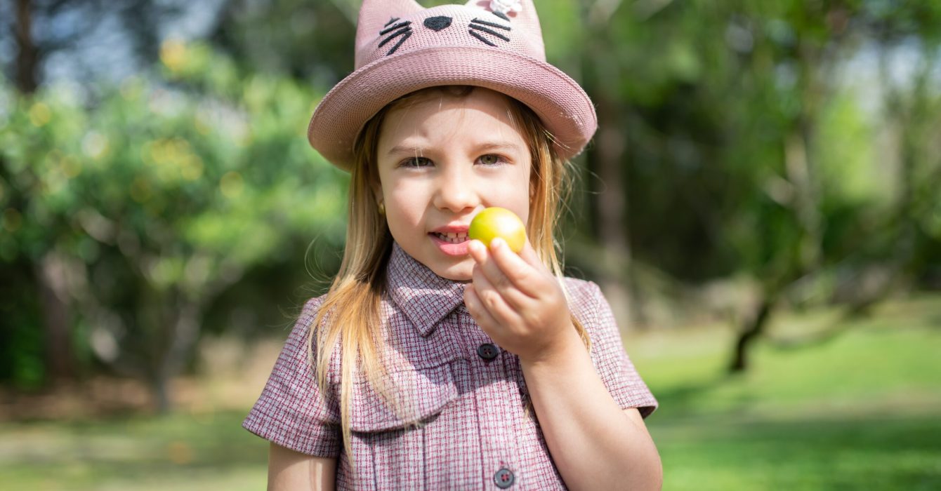 A young girl holds up an Easter egg she's just found in a scavenger hunt in a park.