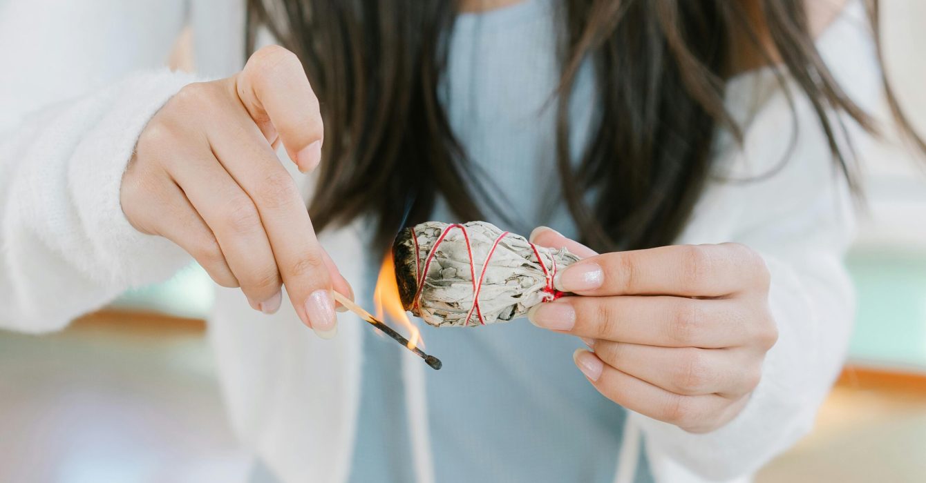 A woman lights some sage to smudge her home