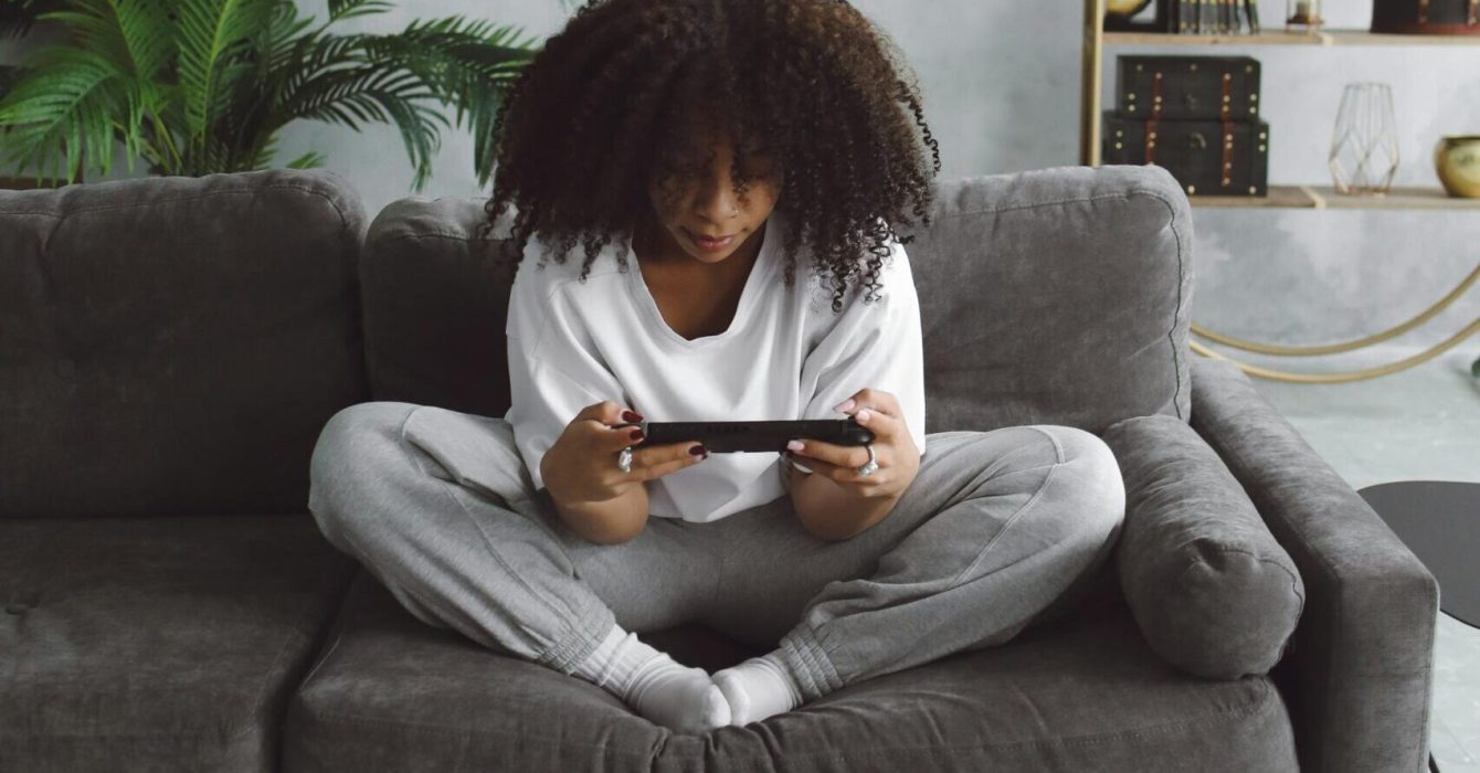 a woman looking cosy gaming on a sofa with a Nintendo switch