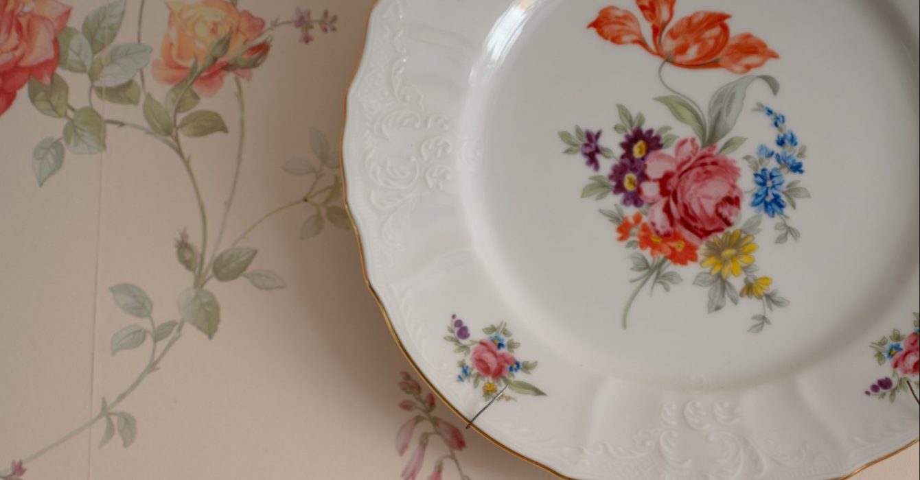 A chintz plate on a patterned tablecloth.