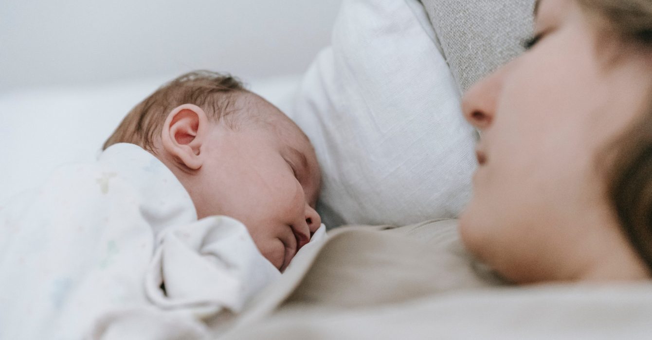 A mother and baby sleeping peacefully next to each other.